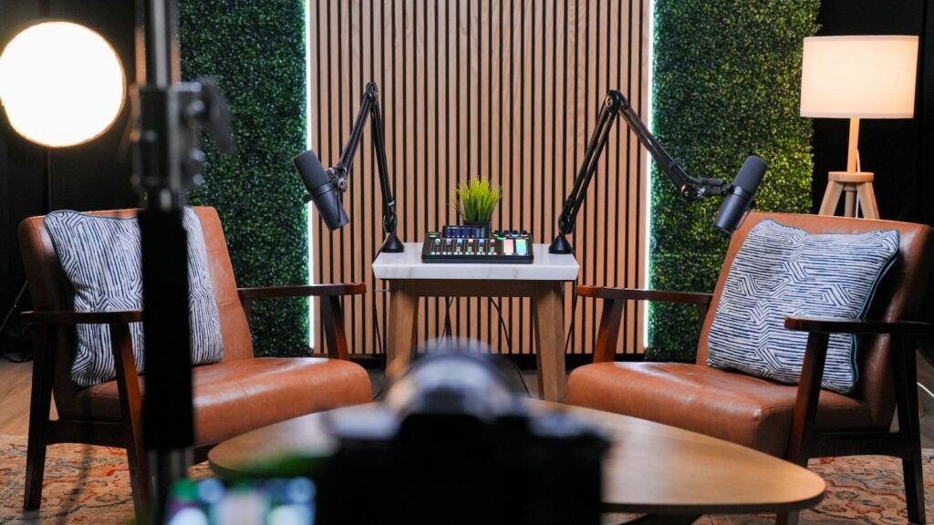 Modern podcast studio interview set with leather chairs, professional microphones, video lighting, and wood slat backdrop in Temecula California